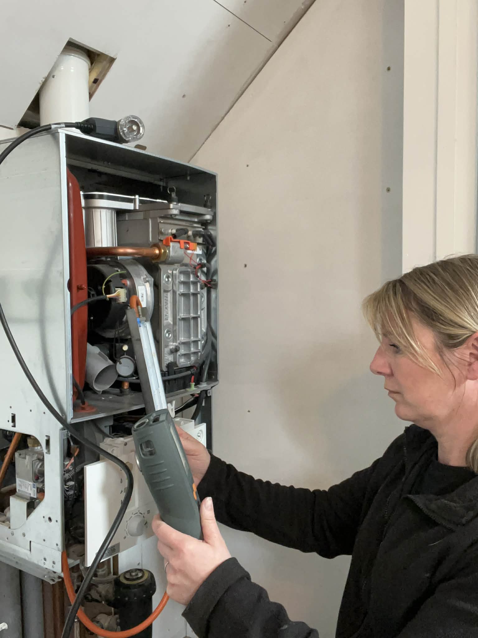 Louise Bee, female gas engineer servicing a boiler in Dereham