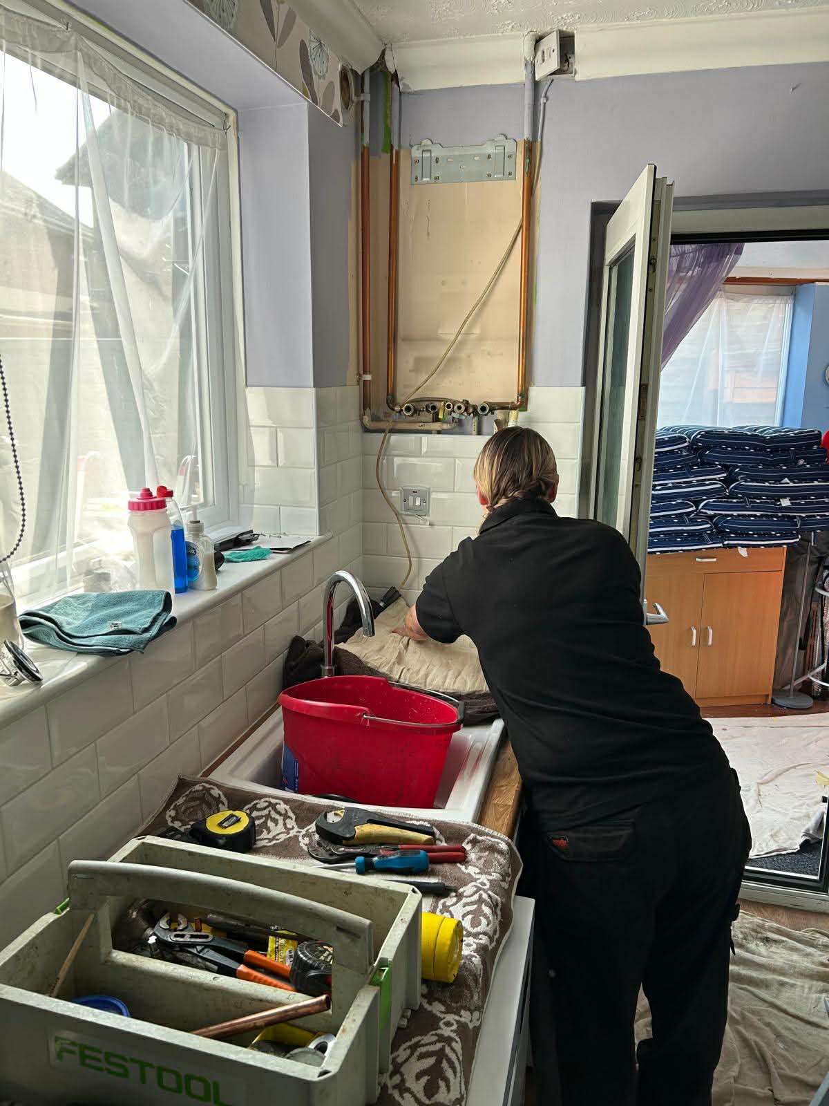 Louise Bee installing a boiler in a customer's kitchen